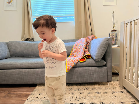 Toddler eating popsicle in front of couch with handmade quilt