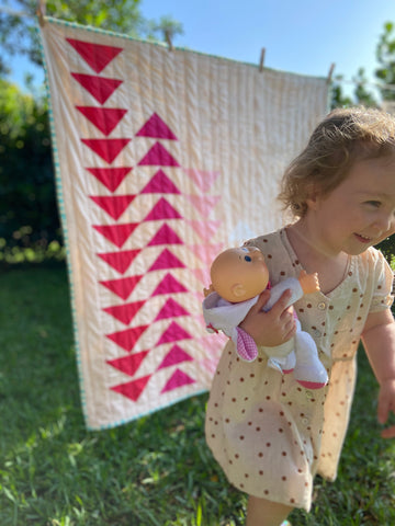 toddler girl running in front of quilt with toy